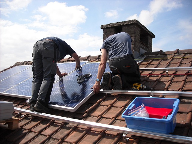 2 men installing a solar panel on a roof