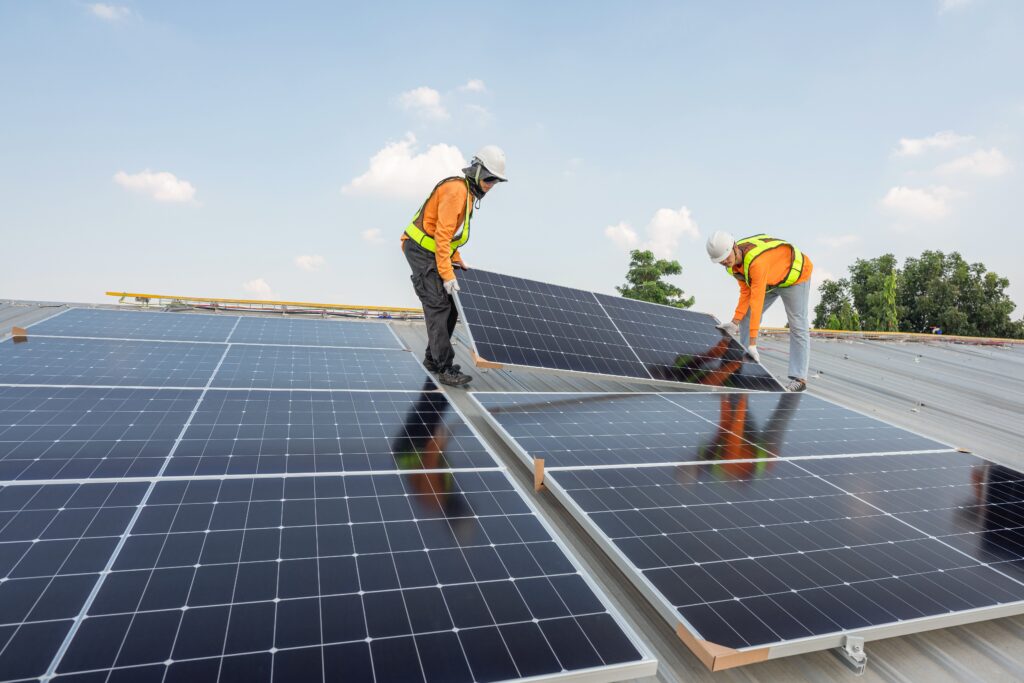 Men,Technicians,Carrying,Photovoltaic,Solar,Moduls,On,Roof,Of,Factory