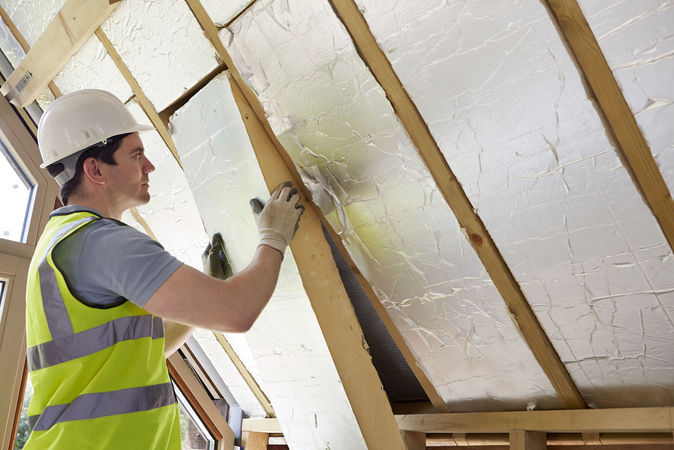 Builder,Installing,Insulating,Board,Into,Roof,Of,House