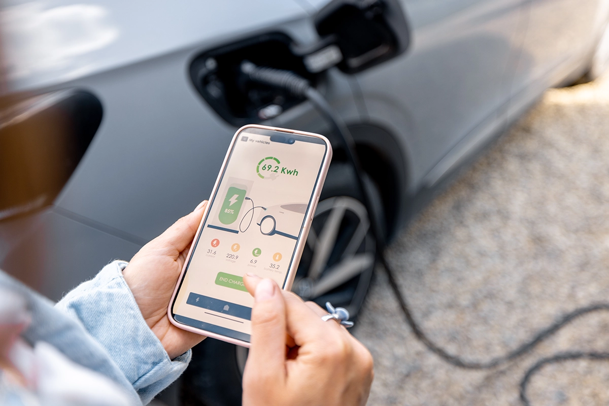 woman charging EV using smartphone app to calculate battery percentage
