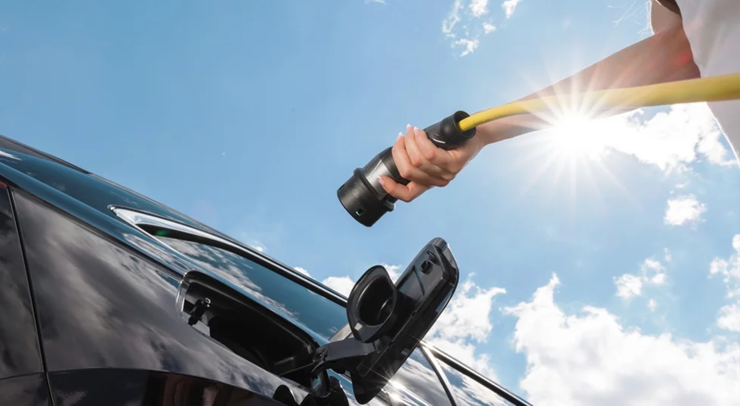 Woman plugging in an EV charging cable in the sun