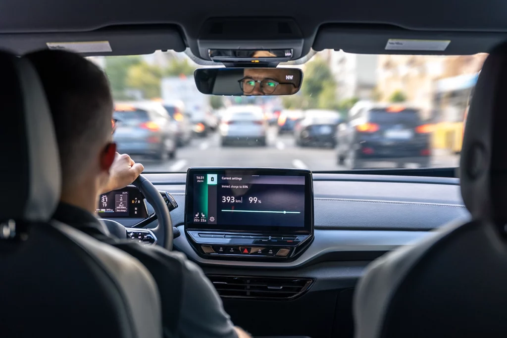 Man driving a fully charged electric car through traffic