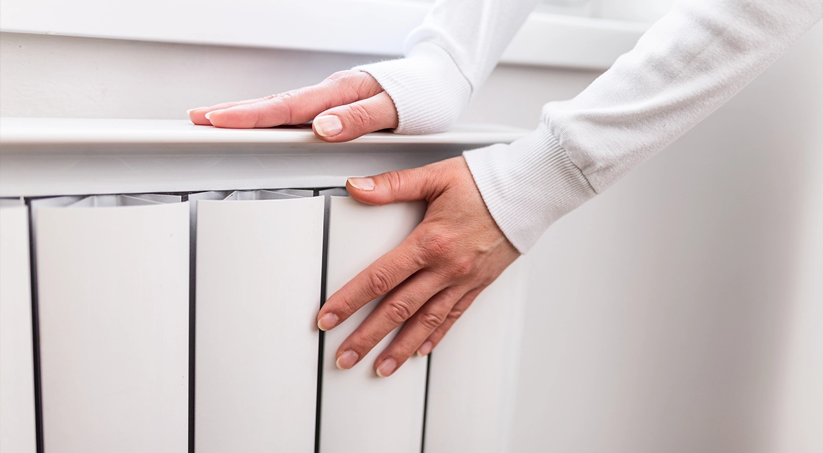High Temperature Heat Pumps Woman touching a wide panel radiator